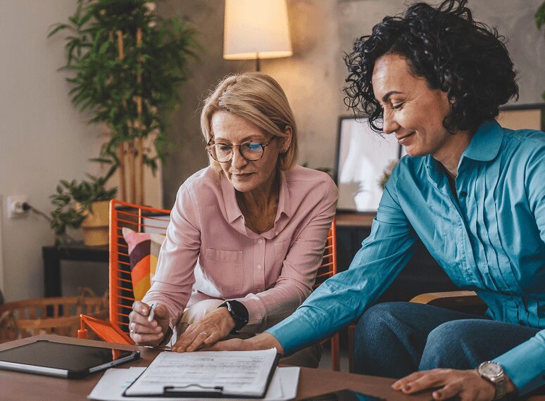 Two women reviewing documents at table.