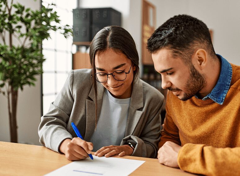 Two people reviewing and signing a document.