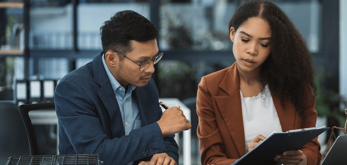 Two colleagues discussing documents in an office.